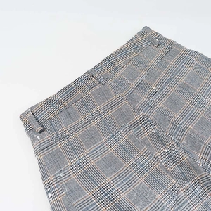 Close-up of high-waist plaid trousers with precise stitching and grey Prince of Wales check