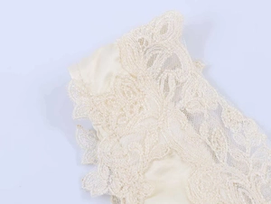 Dettaglio del body in raso color crema con ricami floreali intricati e pizzo raffinato