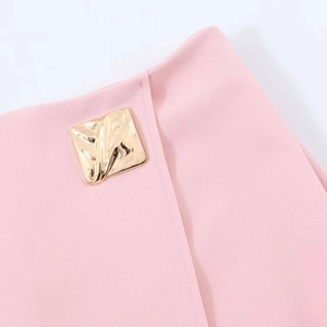Detail view of pink skirt waist with textured fabric and square golden metallic button