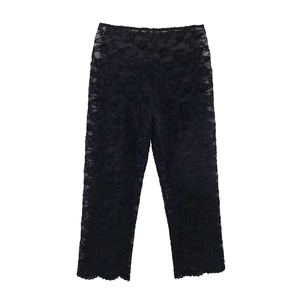 Détail d'un pantalon en dentelle noire avec motifs floraux et broderies semi-transparentes