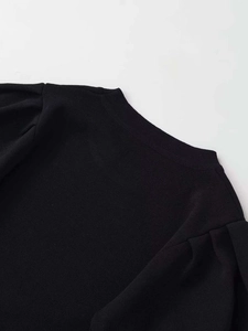 Detail von Rundhalsausschnitt und Puffärmelfalten bei einem schwarzen Strickoberteil