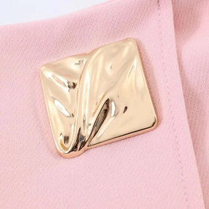 Detailed macro shot of a golden square metal buckle on pink asymmetric skirt fabric
