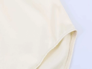Dettaglio del body in raso beige che mostra la trama saia e le cuciture precise