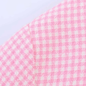 Detailaufnahme der rosa-weißen Hahnentritt-Tweed-Textur an einem Damenjacken-Ärmel