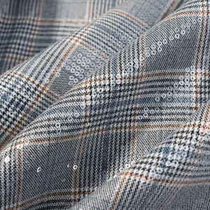 Detailed macro shot of sequined plaid fabric texture with gray and blue checked pattern
