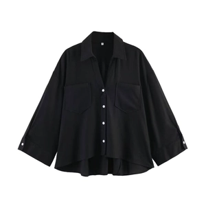 Flat lay of black loose-fit shirt with deep V-neck, chest pockets, and white buttons