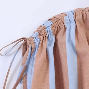 Detail of smocked elastic waistband and drawstring on light blue striped linen shirt