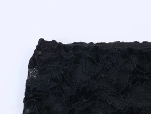 Gros plan sur la dentelle florale noire aux motifs ajourés et détails d'ourlets ondulés