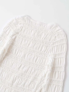 Detailed view of the intricate smocked texture on this white long-sleeve knit cardigan