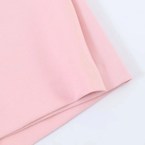 Detail shot of the pink skirt fabric showing fine diagonal weave texture and quality