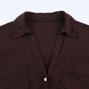 Detail of dark brown shirt collar with V-neckline and white buttons on textured fabric