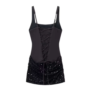 Détail de robe noire avec dos croisé style corset et ourlet orné de sequins brillants