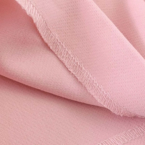 Detailed macro view of pink fabric with high-quality white overlock stitching and texture