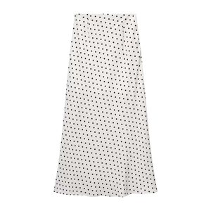 Détail d'une jupe mi-longue évasée blanche légère avec motif classique à pois noirs