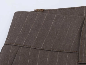 Macro shot of striped brown fabric texture and seam detail of wide-leg trousers