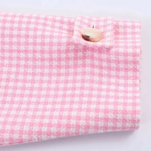 Ärmeldetail der rosa-weißen Tweedjacke mit Hahnentrittmuster und bernsteinfarbenem Knopf