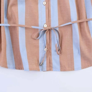 Detail view of vertical striped shirt with white buttons and waist drawstring closure