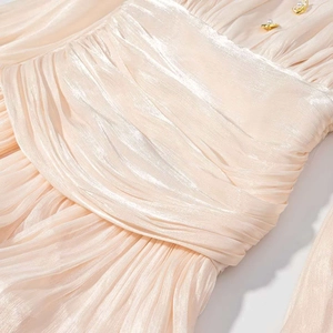 Gros plan sur le tissu satiné plissé champagne et les boutons de perles dorées