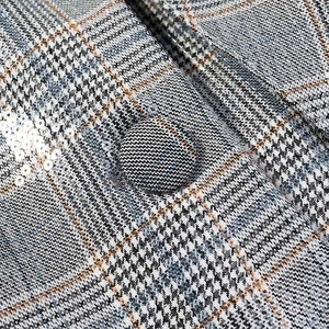 Detail of plaid fabric with sequins and a matching fabric-covered button for a blazer