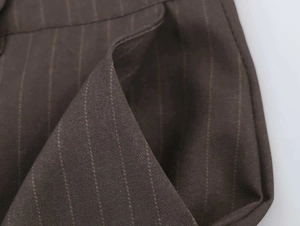 Detailed view of the side pocket and fine stitching on dark brown striped trousers