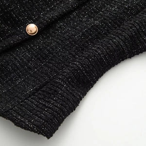 Close-up of black tweed fabric with metallic silver threads and rose gold button detail