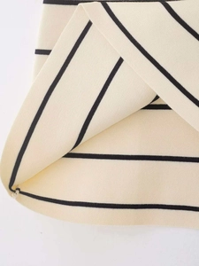 Détail du tissu en maille douce avec rayures crème et noires et finition soignée