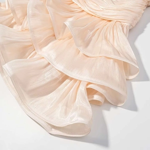 Vue détaillée du tissu plissé pêche avec texture de soie et couches de volants élégants