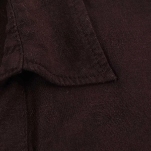 Close-up of double stitching and breathable linen fabric texture on dark brown shirt
