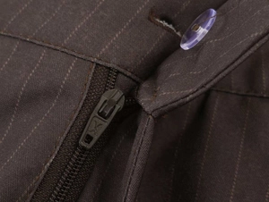 Detail view of the brown striped trousers showing the metal zipper and clear button closure