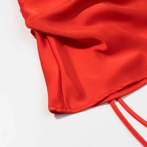 Detail of red satin dress featuring a smooth silk texture and fine hemline stitching