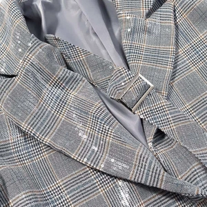 Detail of grey prince of wales check blazer with subtle sequins and silver metal buckle