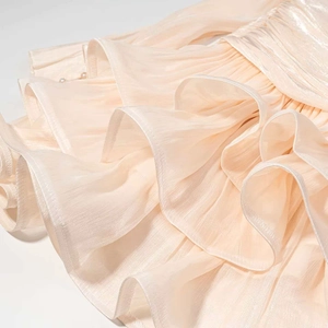 Détail de la robe champagne à manches longues avec texture plissée et volants