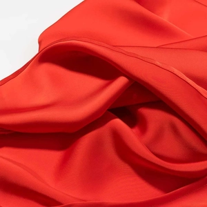 Detailed close-up of smooth red satin fabric with high-quality hemmed edges and silk texture