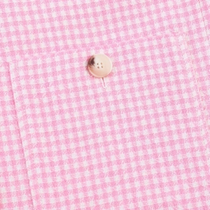 Detail von rosa-weißem Hahnentritt-Stoff mit einem marmorierten Harzknopf an der Jacke