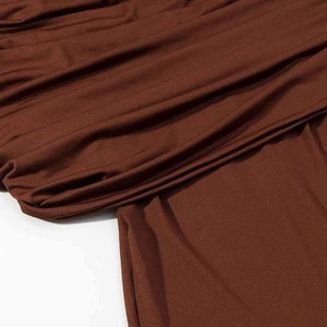 Détail du tissu à paillettes marron foncé présentant des fronces élégantes et drapées