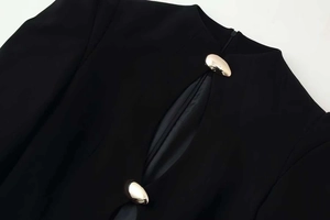 Détail de la robe noire avec découpes et boucles métalliques dorées en forme de goutte