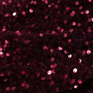 Vue macro de paillettes bordeaux scintillantes sur tissu en velours pour robe femme