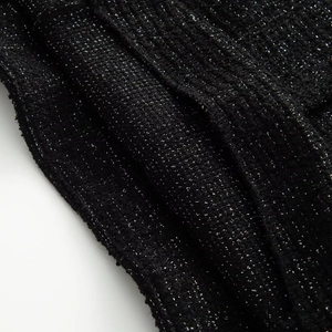 Close-up detail of black tweed fabric featuring sparkling silver metallic thread texture