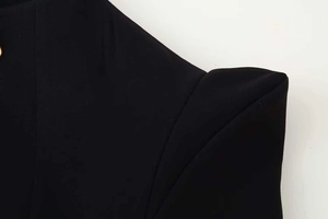 Gros plan détaillé d'un blazer noir avec épaulettes structurées et détail de bouton doré