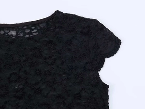 Gros plan d'un haut en dentelle noire avec motifs floraux et détails de bords festonnés