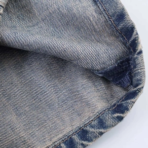 Detailed macro view of blue denim fabric showing yellow double stitching and twill texture