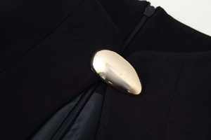 Détail de robe noire avec boucle ovale dorée polie et fermeture à glissière lisse