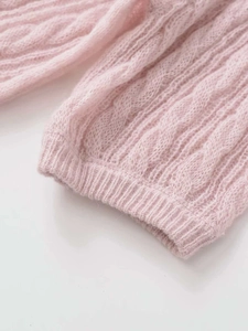 Close-up of soft pink cable-knit texture and ribbed cuffs on the fuzzy mohair sweater