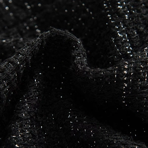 Macro shot of shimmering black tweed fabric with metallic silver threads and rich texture