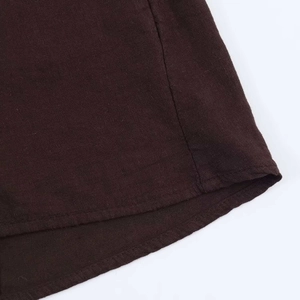 Detail of curved hemline and stitching on a coffee-colored cotton linen shirt