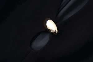 Détail de la boucle dorée sur la découpe en goutte d'eau de la robe noire ajustée chic
