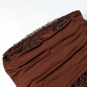 Gros plan sur le tissu froncé marron de la robe avec détails de bordure en sequins noirs