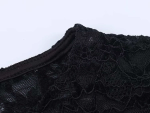Détail macro du col en dentelle florale et de l'ourlet de cet ensemble noir deux pièces