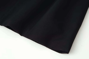 Gros plan sur le tissu tissé noir montrant la texture fine et le drapé élégant de la robe