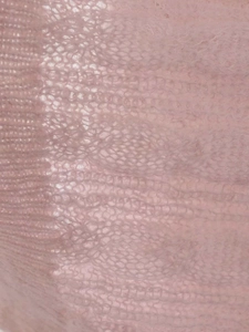 Close-up detail of soft pink knit texture with twisted cable pattern and mohair fiber